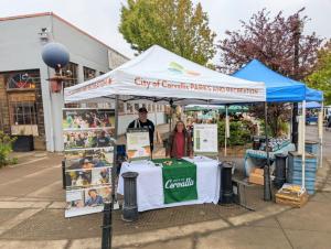 Mayor and City Councilor staffing a table at the farmers market.
