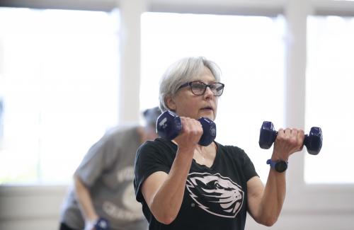 woman lifting weights in group class wearing OSU Beaver shirt