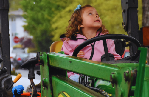 A girl sitting on a John Deere tractor. 