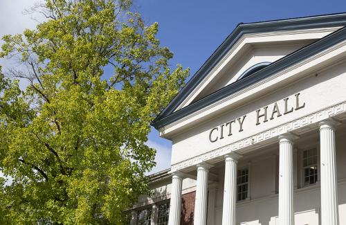 Corvallis City Hall with a green tree to the left, on a clear day with a sunny blue sky overhead.