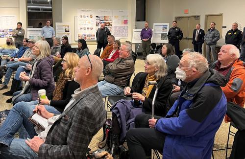 About 20 to 30 visitors in the Library meeting room listening to the speaker talk about the city facilities project