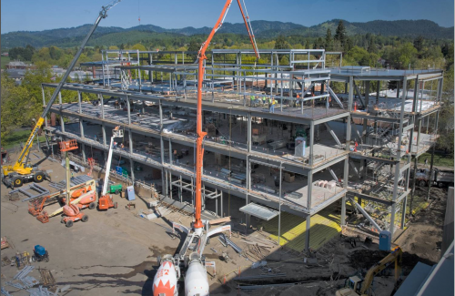 Cranes lifting beams onto metal structure