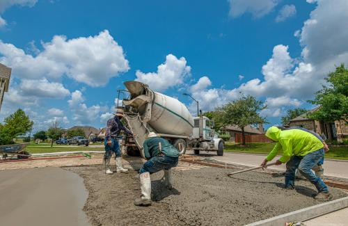Concrete truck pouring new driveway from the right of way with construction workers