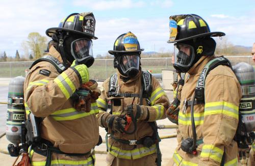 3 volunteer firefighters in yellow coats and breathing masks