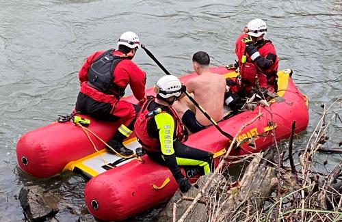 CFD Water Rescue Two rescue swimmers on a red inflatable raft tend to a victim.