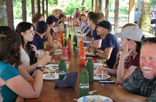 City employees seated at a long table enjoying lunch outdoors at the annual picnic.