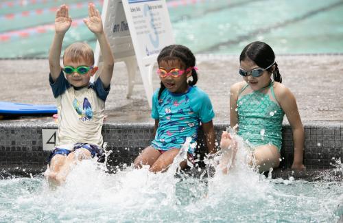 three kids learning to kick legs to swim