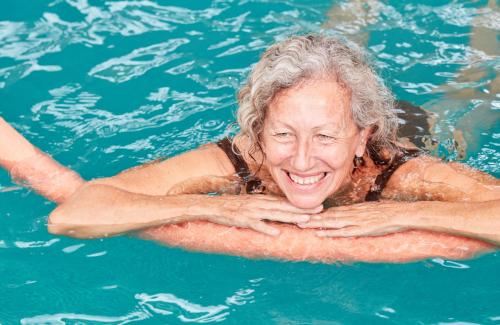 senior woman swimming with pool noodle