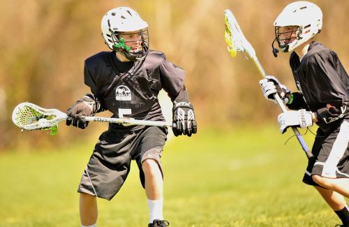 Two kids in black uniforms playing lacrosse