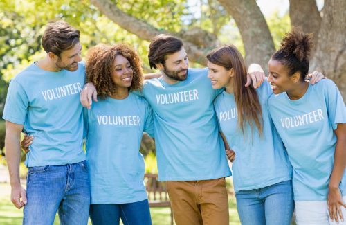 Five adults in a natural forested area, all wearing "Volunteer" shirts