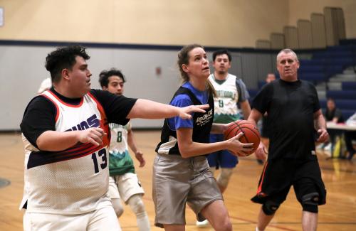 coed basketball game, woman holding ball while defender man chases to get in position