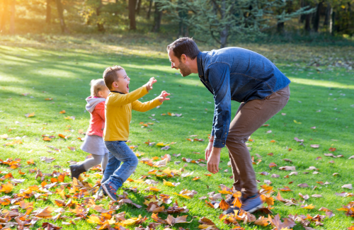 young kids excitedly running to dad in park