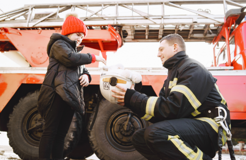 fireman handing kid his helmet to look at