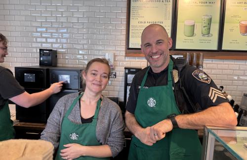 A Starbucks barista and a police officer, both wearing aprons during Coffee with a Cop