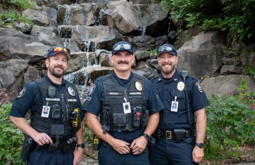 Three police officers stand in front of a landscaped water feature