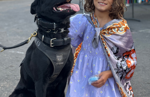 K9 Mazikeen, a black dog, and a young girl in a purple dress at National Night Out