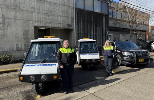 Two parking enforcement scooters and two parking enforcement officers outside in front of the police station