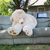 Large teddy bear on a couch on the curb