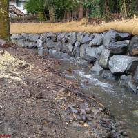 Creek with newly installed retaining wall made from rocks