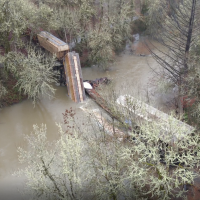 Overhead photo of Marys River with collapsed train trestle and several derailed train cars 