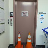 Elevator with an out of service sign and two orange hazard cones blocking the door