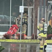 Firefighters wearing hazardous materials gear make entry into Oregon State Credit Union.