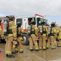 Firefighters in turnout gear standing near a red fire engine