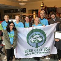 Neighborhood tree stewards posing with a big while Arbor Day flag