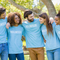 Five adults in a natural forested area, all wearing "Volunteer" shirts