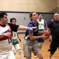 coed basketball game, woman holding ball while defender man chases to get in position