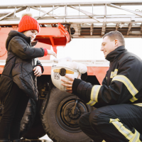 fireman handing kid his helmet to look at