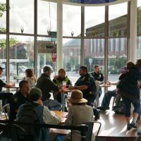 Police officers having coffee with community members at a local coffee shop on a sunny morning.