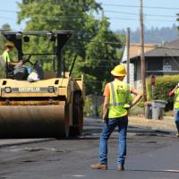 Foreman standing in front of an asphalt smoother.