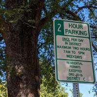 Residential parking permit sign on a post with a tree in the background