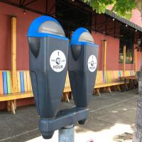 Parking meter on the sidewalk next to a rainbow colored restaurant facade.