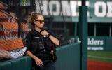 A female officer in sunglasses watches a softball game