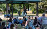 Officers read in a park gazebo to a large group of children