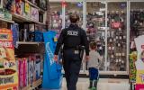 An image of an officer and small child from behind shopping for Christmas gifts