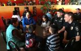 Officers and community members seated at a table enjoying a cup of coffee together.