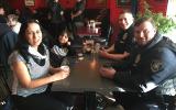 Officers and community members seated at a table enjoying a cup of coffee together.