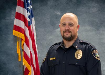 Captain Dan Duncan, in front of a blue background and American flag