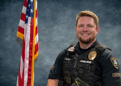 Lieutenant Matt Seney, in front of a blue background and American flag