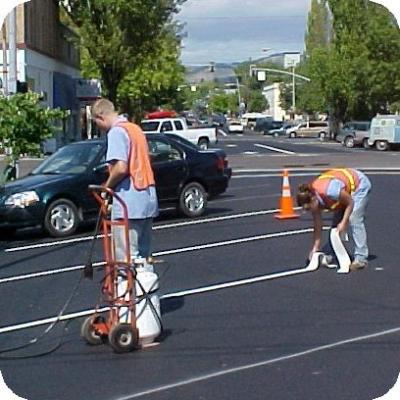 Two public works employees laying parking stripes
