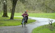 Corvallis Cyclist on a rainy path with green grass