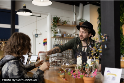 A barista handing a customer a drink at a cafe.