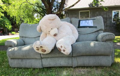 Large teddy bear on a couch on the curb