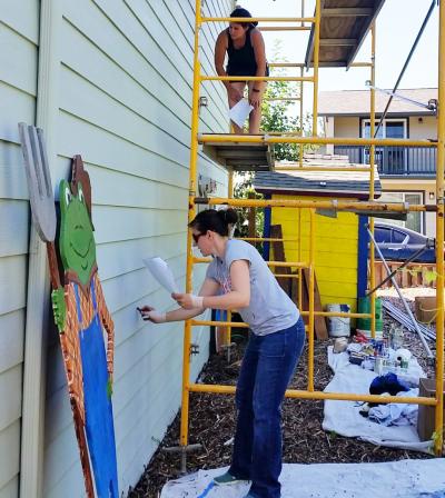 Artist painting a mural on the side of a building