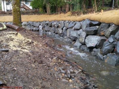 Creek with newly installed retaining wall made from rocks