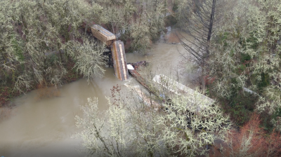 Overhead photo of Marys River with collapsed train trestle and several derailed train cars 