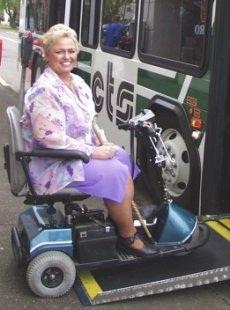 old lady getting on a bus in a wheel chair
